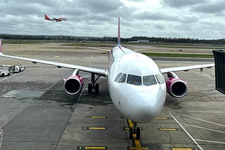 A Wizz Air A321 plane sits at the departure gate of an airport.