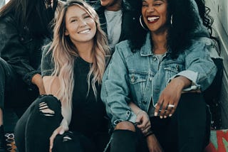 Women from diverse groups sitting together on a staircase smiling and connecting with each other