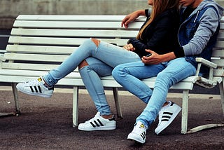 Couple in jeans sitting on the banch