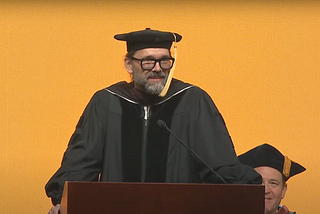 a photo of R. Michael Hendrix, standing at the podium in cap and gown