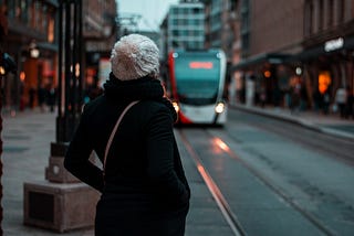 A woman waiting for the bus that is reaching her.