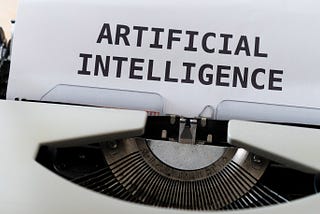 piece of paper in a typewriter has the words “artificial intelligence” typed on it