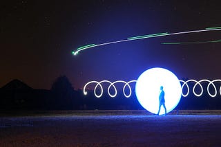 A person walking outside at night time with shooting stars in the sky.