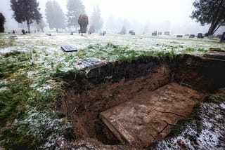 A snow covered field with an old casket in an open grave
