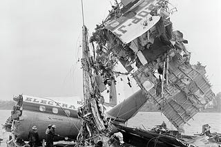 wreckage of crashed passenger airplane lifted by crane onto barge