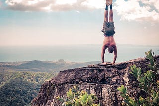 How to instantly improve your handstand header image. The author doing a handstand on the edge of a cliff in Krabi, Thailand.
