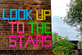 Brick wall with the words “Look up to the starts” written on it.