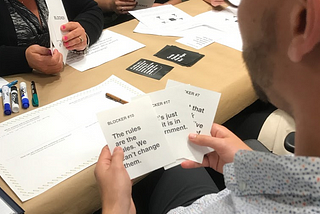 Photo of a man holding three blocker cards while playing the CaHMW game.