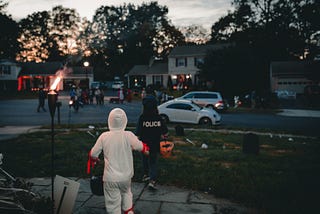 two children running in their neighborhood, on Halloween