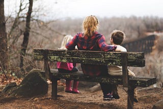Woman sitting on a bench with her two kids