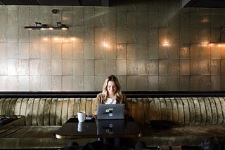 Blonde woman working in her laptop at a cafeteria.