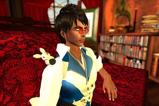 A screenshot from Second Life. A 3D rendered man with tan skin, wearing round, rose coloured glasses, white shirt and a blue and white striped vest. His hair is short, brown and tousled. On his shoulder sits a small white rabbit. He is sitting on a luxurious red brocade chair and looking off into the distance. The room looks to be a personal library, with timber fittings and stacks of books on bookshelves.