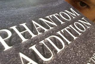 The book cover for Phantom Audition with author’s eyes peering over it