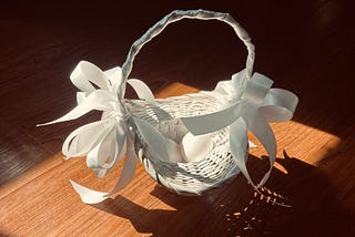 White basket with white ribbons with two white chicken eggs inside