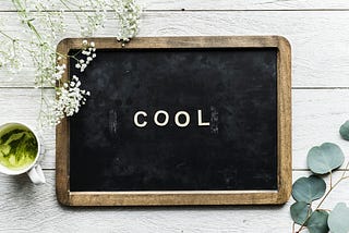 A small aesthetically designed blackboard with the words “cool” written in chalk