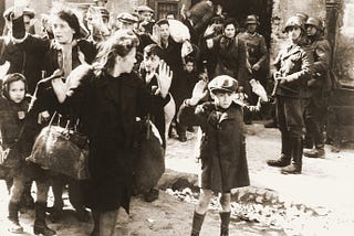 A roup of Polish Jews captured by German soldiers during the suppression of the Warsaw Ghetto Uprising (Poland). Some are women with raised hands. One is a little boy, also with hands raised.