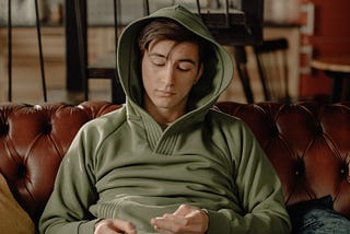 Man in Gray Hoodie Sitting on Brown Leather Couch