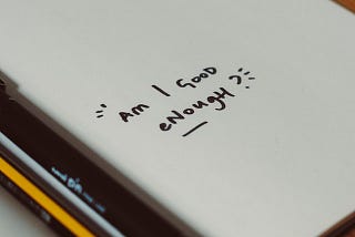 A white page says “Am I good enough?” written in black marker