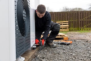 Image shows a heat pump installer working at a domestic property in Glasgow.