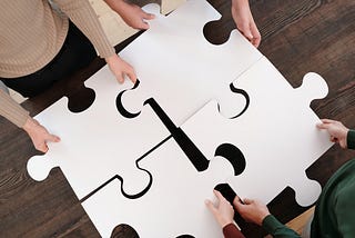 four people holding four big peaces of puzzle and joint them together