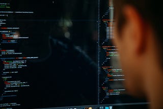 Close up of a person looking at code on a computer screen.