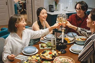 Four people toasting at the dining table.