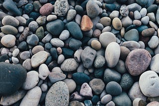 A pile of soft, rounded and speckled weathered stones and pebbles