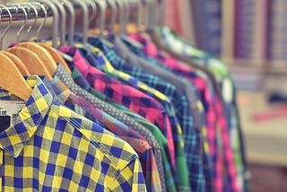 Assorted colorful plaid shirts hanging next to each other on a rack