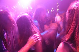 The slightly blurred image of some partygoers dancing in a nightclub.