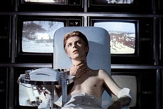 David Bowie in the film The Man Who Fell To Earth watching multiple TV screens