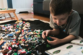 A kid making lego creations from an inspiration book.