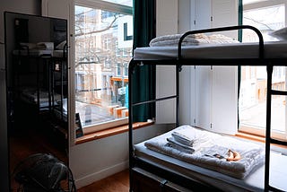 2 beds in the corner and two windows on each side of the wall.