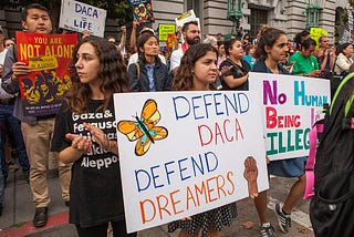 Protesters in San Francisco hold signs with slogans such as “Defend DACA” and “No human being is illegal”.