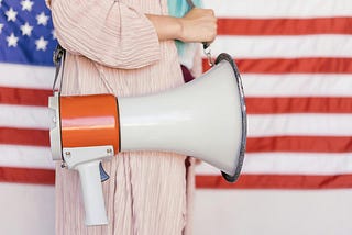 Woman standing in front of the American flag with a megaphone
