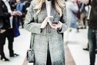 photo of a young woman staring at her phone in a crowded public space, symbolising digital distraction and modern disconnection