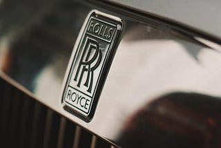 Photo of the “Double R” logo on the front of a Rolls Royce front grill.