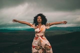 photo of woman in colorful dress with spread arms in nature