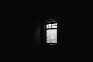 black walls, and an uncurtained window.