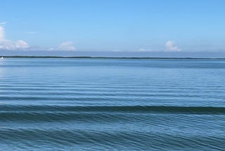 Ocean landscape with shallow wave and clouds on horizon.