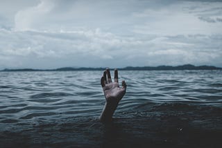 A hand reaching out of the ocean towards the sky