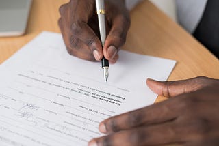 A person’s hands holding a fountain pen, signing a document