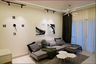 Living room with couch, clock, and lamp. Interior design by Kolkata designers.