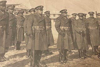 Photo of Soldiers from the 92nd Infantry Division, standing in formation in Korea on the icy frozen ground. Photo is from the author’s personal collection and of his grandfather, from left to right, 4th person, front row.