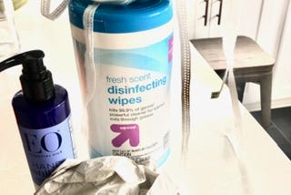 A photo of disinfectant wipes with latex gloves and a respirator mask.