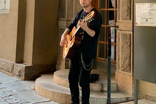A photo of the author playing guitar on the street.