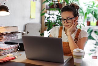 A woman sitting in front of her laptop, preparing user research, smiling.