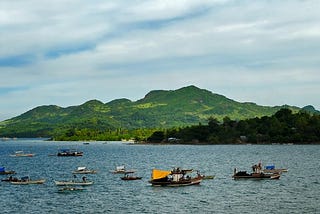 View of the sea with fishing boats and a volcanic island in the distance.