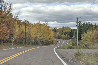 A very winding road through forest in fall.