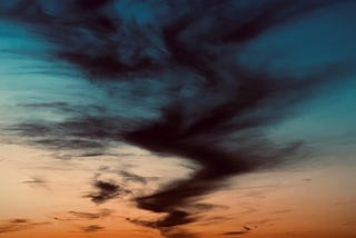 a dark cloud snaking through an evening sky