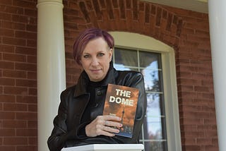 Image of a lady holding her own book that has been published.